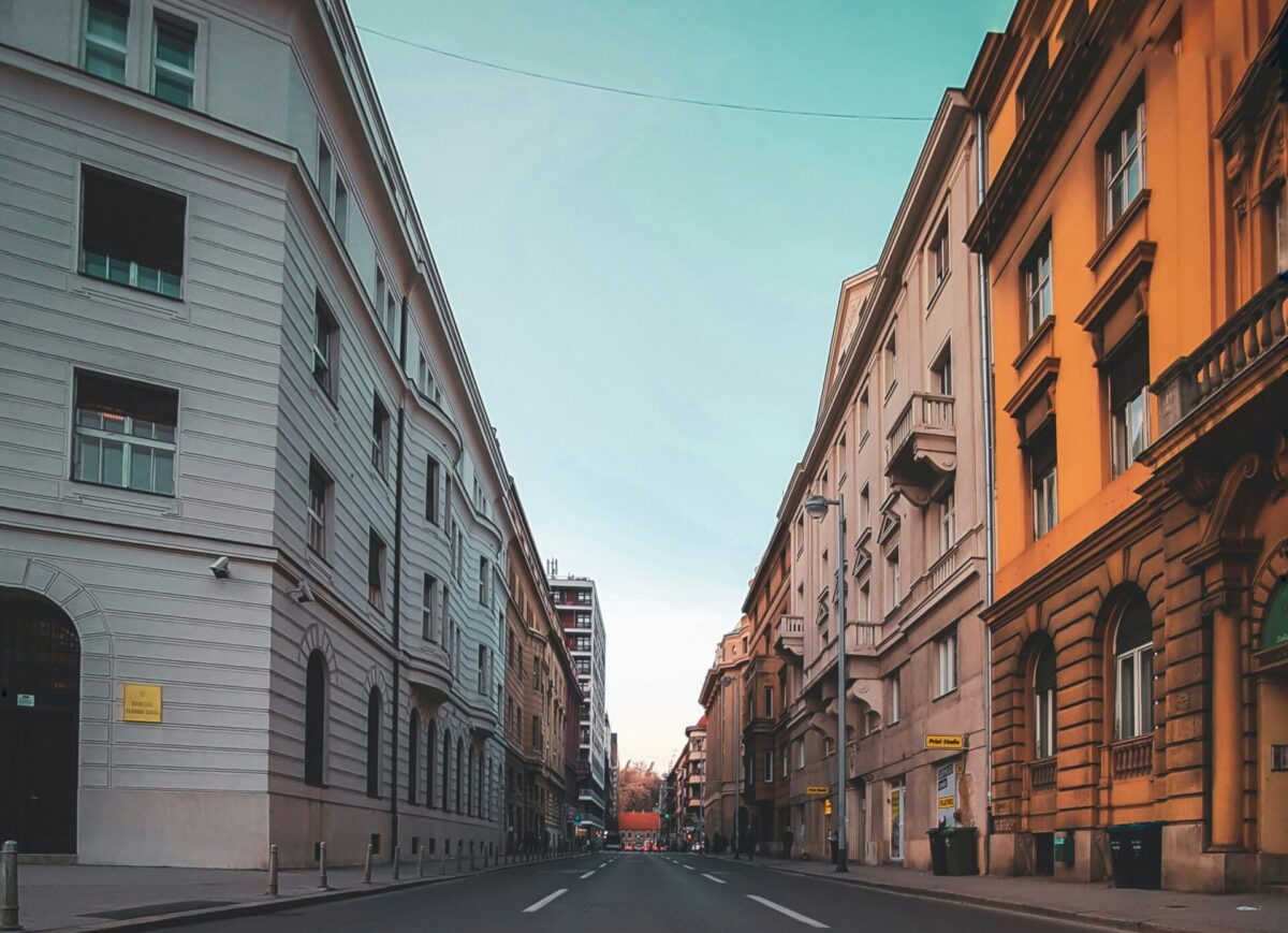 Bild einer Straße innerhalb einer Stadt. Links und rechts sind unterschiedliche Fassaden zu sehen.