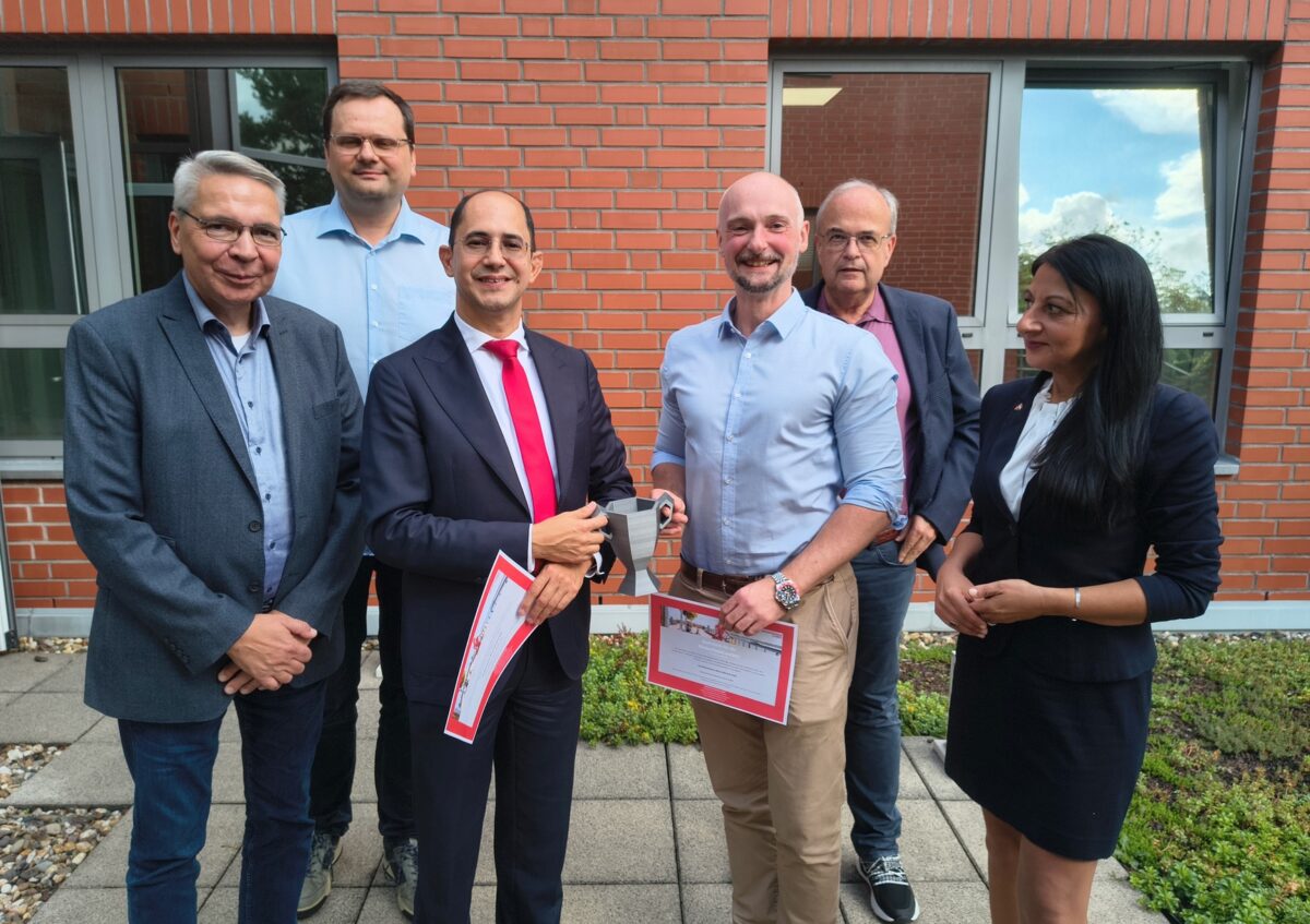 Auszeichnung im Haus der Wirtschaft in Viersen: Daniel Cames von Solbach (l.) und Daniel Szeremley von Rico halten gemeinsam den symbolischen Digital-Pokal. Die ersten Gratulationen kamen von (v.l.): Dirk Letter (Togrund), Sebastian Barchnicki (DIGITAL.SICHER.NRW), Dr. Thomas Jablonski (WFG) und Asst. Prof. Dr. Senem Yazici (Hochschule Niederrhein). Foto: WFG
